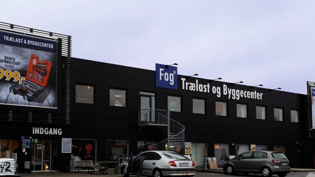 Utvendig bilde av Johannes Fog trelast- og byggesenter i Farum med logo og elektroniske hyllepriser.