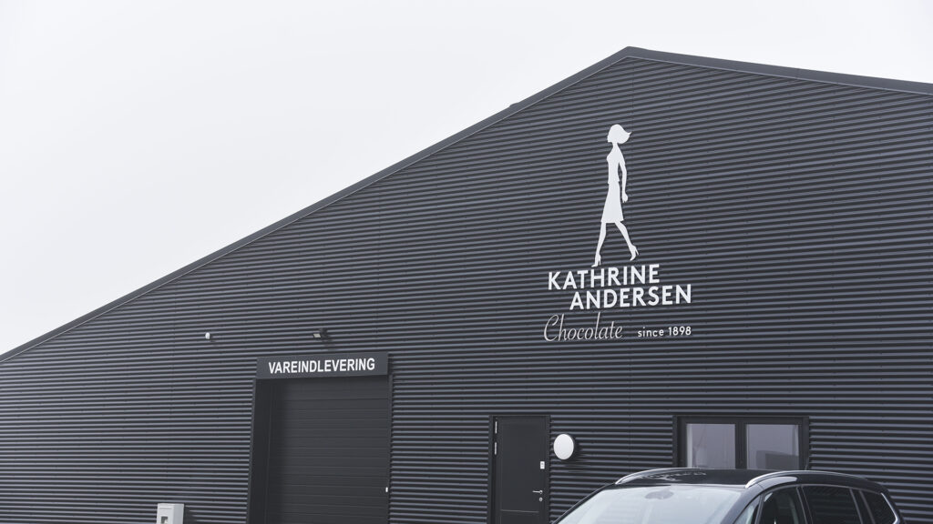 Utvendig fasade av Kathrine Andersen Chokolade-bygningen med logo og varelevering skilt.