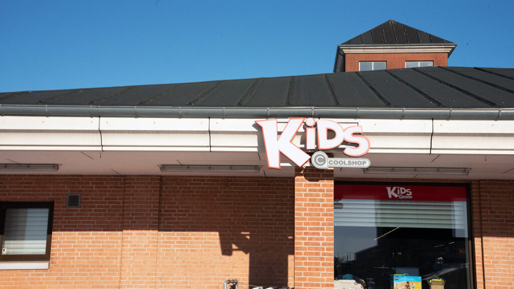 Eksteriør av Kids Coolshop butikken med logo på mursteinsvegg og tak.