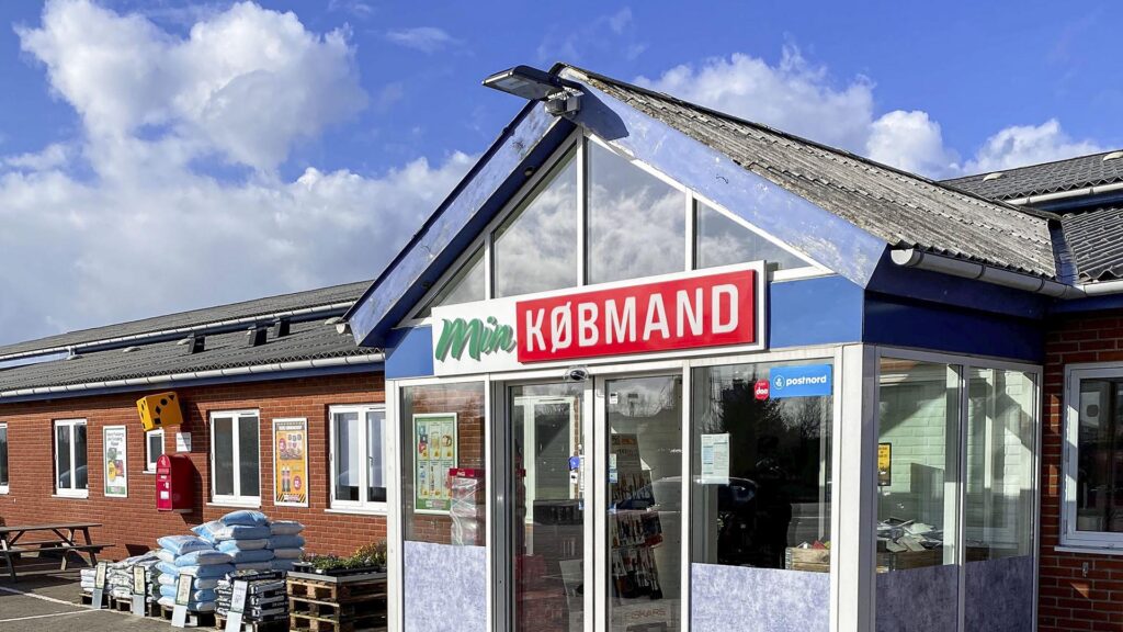 Utvendig bilde av Min Købmand Østerild butikk med skilt og varer utenfor.