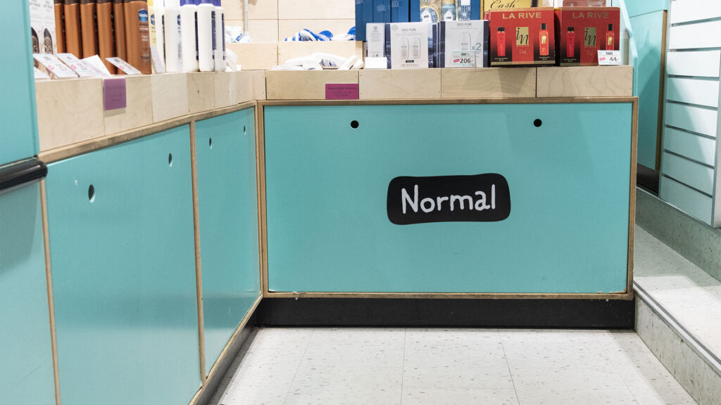 Ladenansicht von Normal mit türkiser Kassentheke und Regalen.