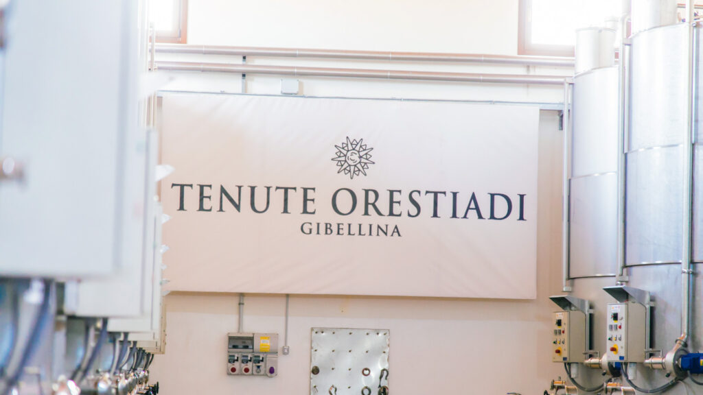 Tenute Orestiadi logo banner i en vinproduktionsfacilitet.