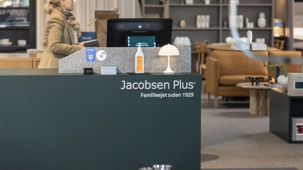Kassebereich mit Jacobsen Plus-Logo und elektronischen Preisschildern im Möbelhaus.