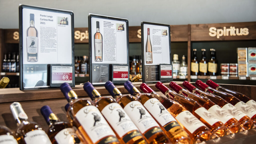 Digitale Preisschilder präsentieren Weinangebote bei VestVin, die grüne Weinhändler stärken.