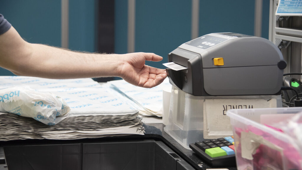 Medarbejder hos Hobbii printer linerless etiketter på en Zebra labelprinter.