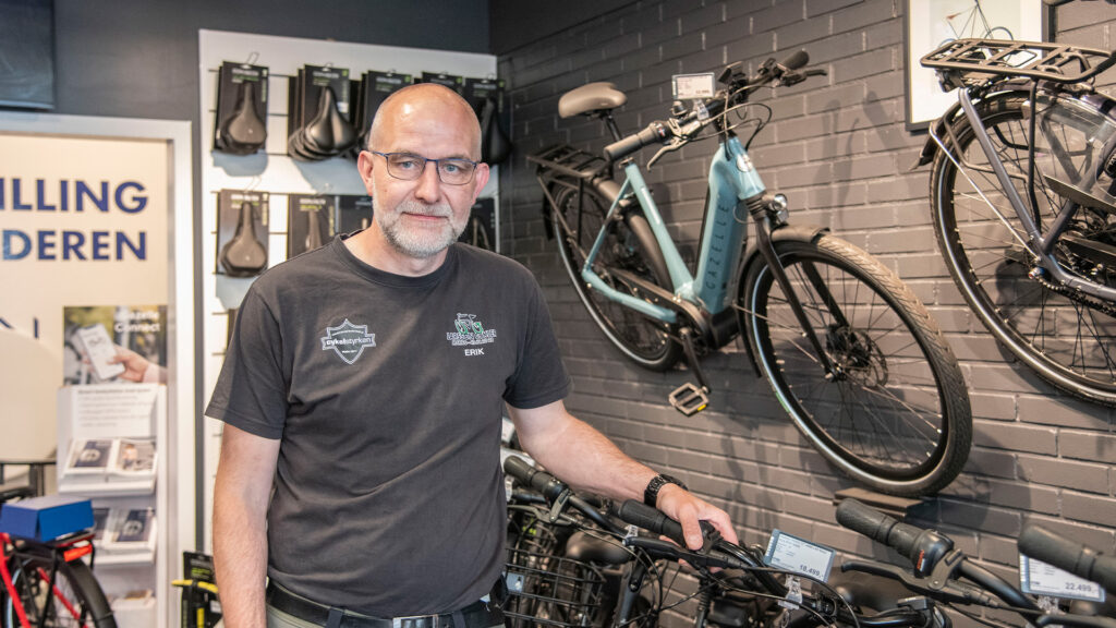 Erik Larsson, Inhaber von Larsson Cykler, steht in seinem modernen Fahrradgeschäft mit digitalen Preisschildern.