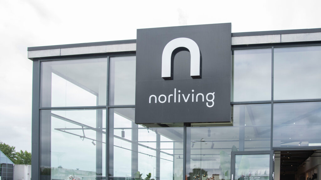 Udvendigt skilt med Norliving-logo på en moderne butiksfacade i glas.