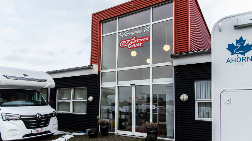 Jysk Caravan Center butiksfacade med digitale prisskilte og campingvogne foran.