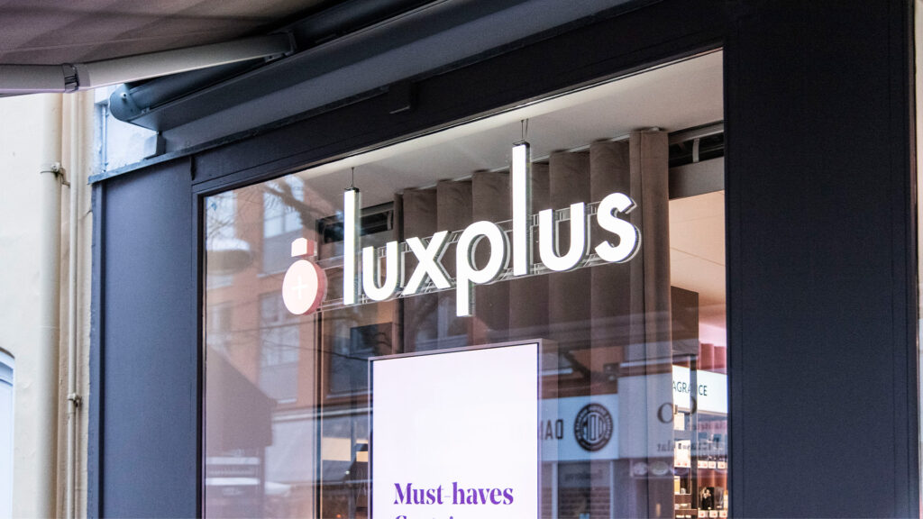 Luxplus Ladengeschäft mit digitaler Beschilderung und Preisen auf Bildschirmen.