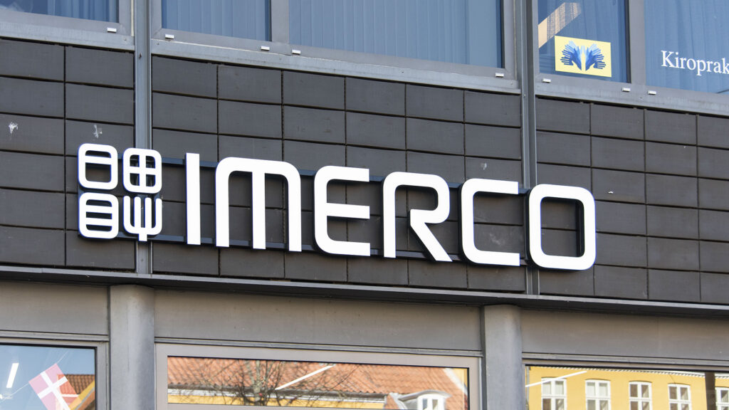 Leuchtreklame mit dem Imerco Logo an einer Gebäudefassade.