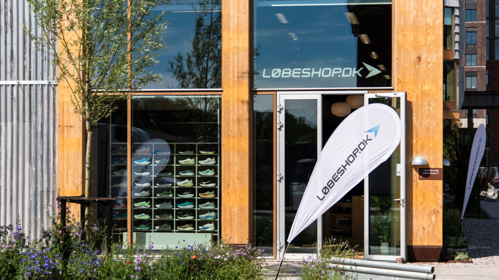 Außenansicht des Løbeshop-Geschäfts in Aarhus mit Logo und Schaufenster voller Laufschuhe.
